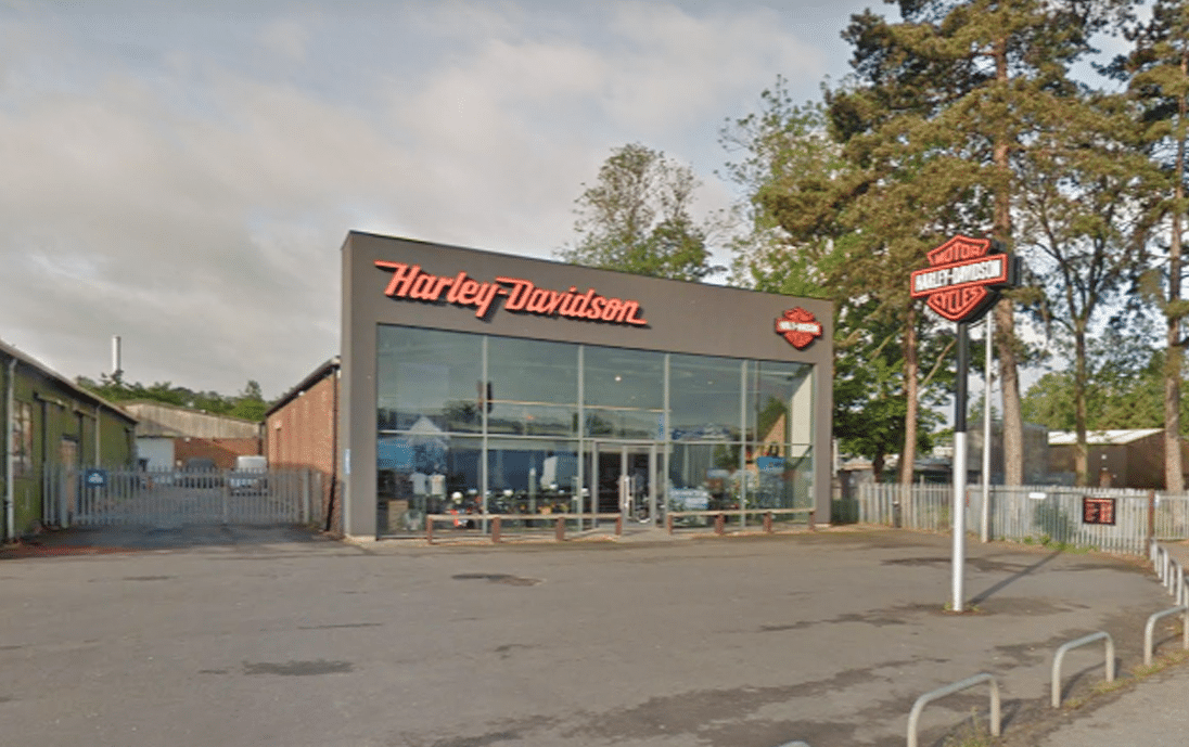 Exterior view of a modern Harley-Davidson dealership with a glass storefront and prominent brand signage
